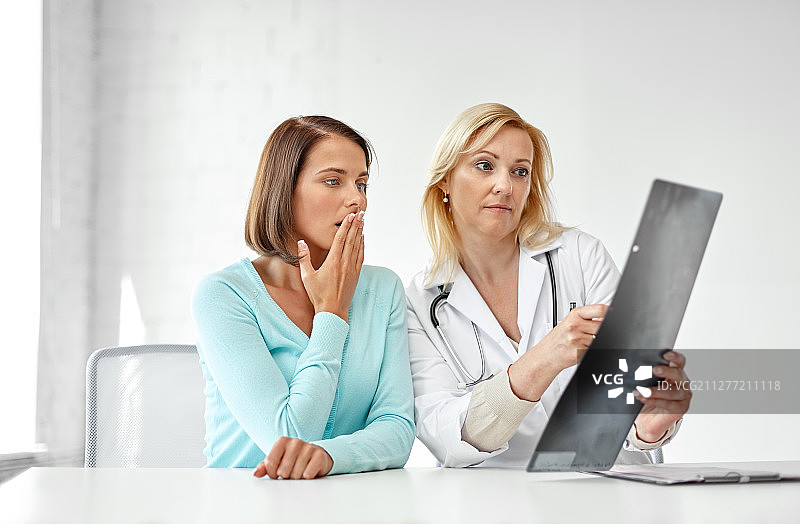 医学、医疗保健和健康问题概念：医生和悲伤的女患者在医院查看脊柱X光片图片素材