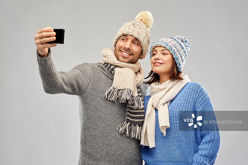 圣诞情侣在灰色背景下用手机自拍图片素材