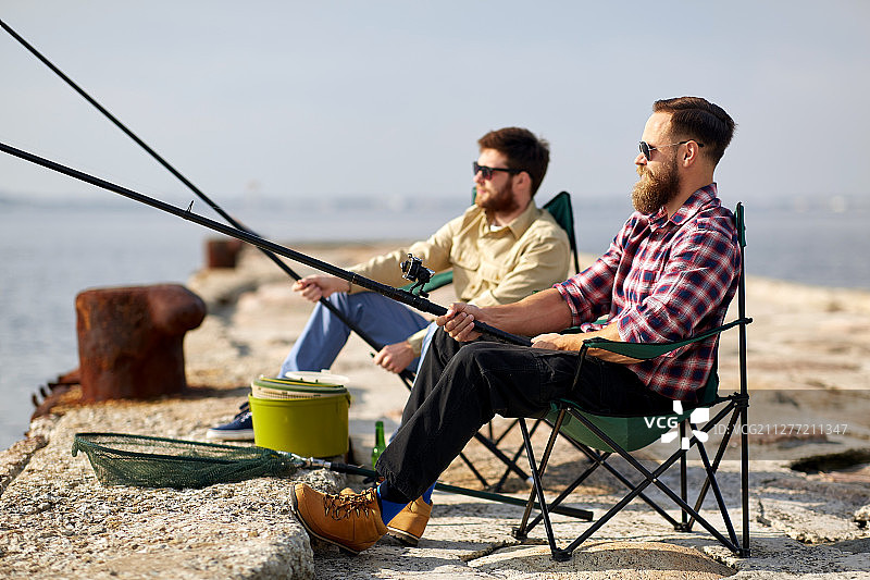休闲概念：朋友们在码头上用钓鱼竿钓鱼图片素材