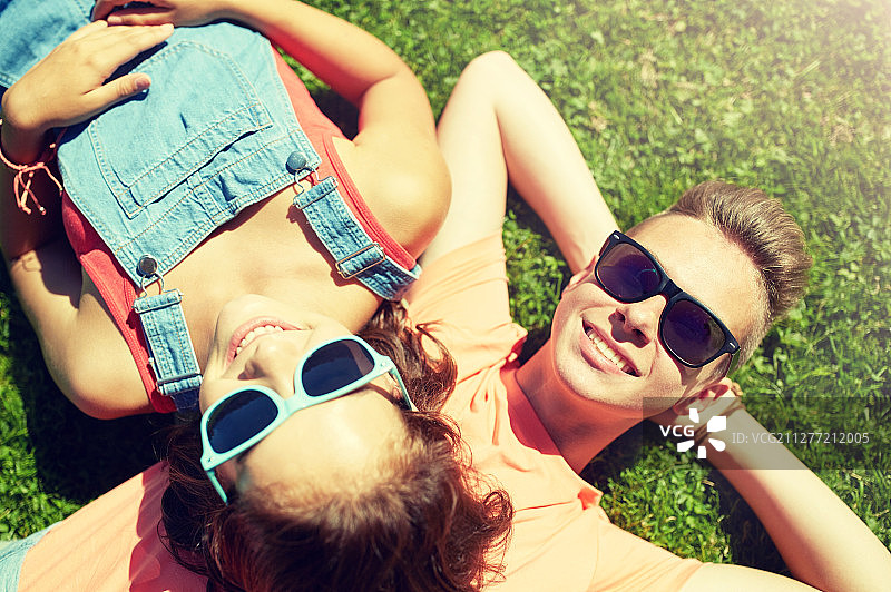爱与人：草地上戴太阳镜的快乐青少年情侣图片素材