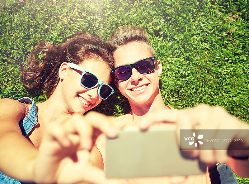 快乐的年轻情侣在夏天用智能手机自拍图片素材