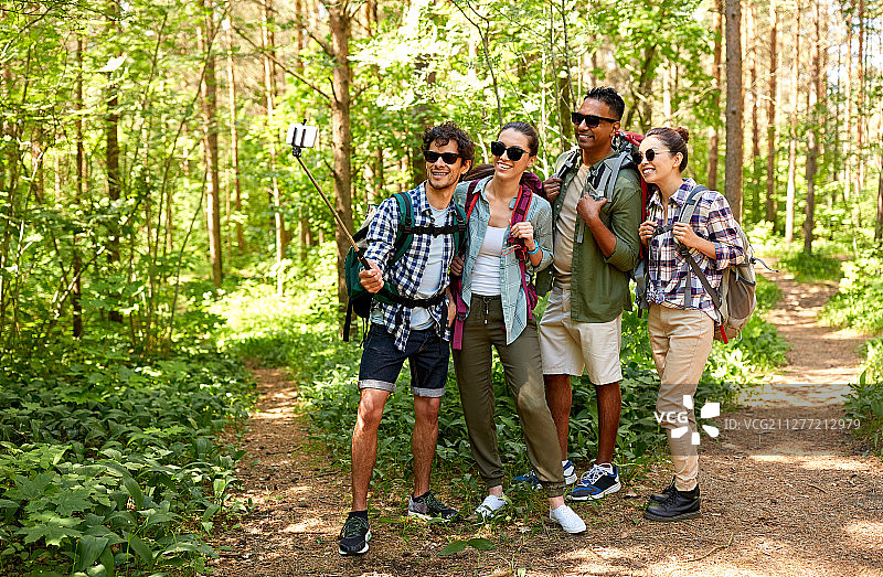 旅行远足概念：朋友们在森林中用手机自拍图片素材