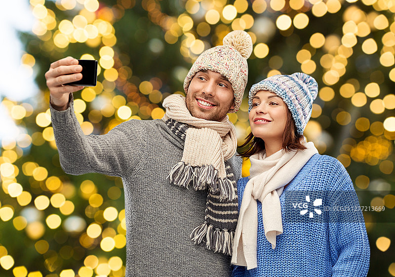 圣诞节戴着针织帽围巾的情侣手机自拍图片素材