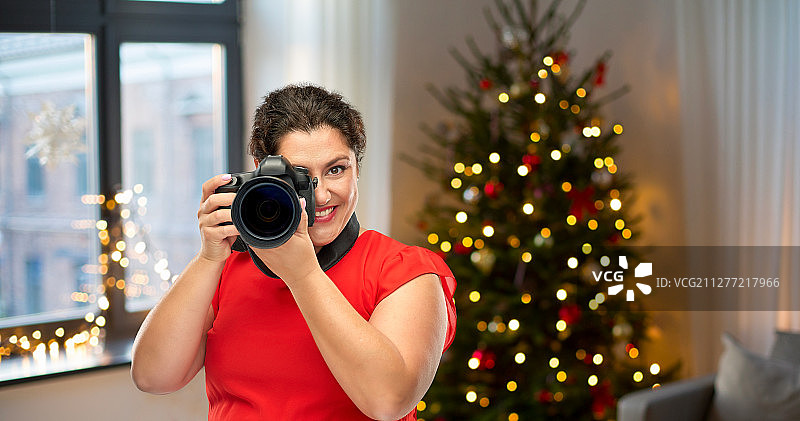 节日摄影概念：红裙摄影师用数码相机拍摄图片素材
