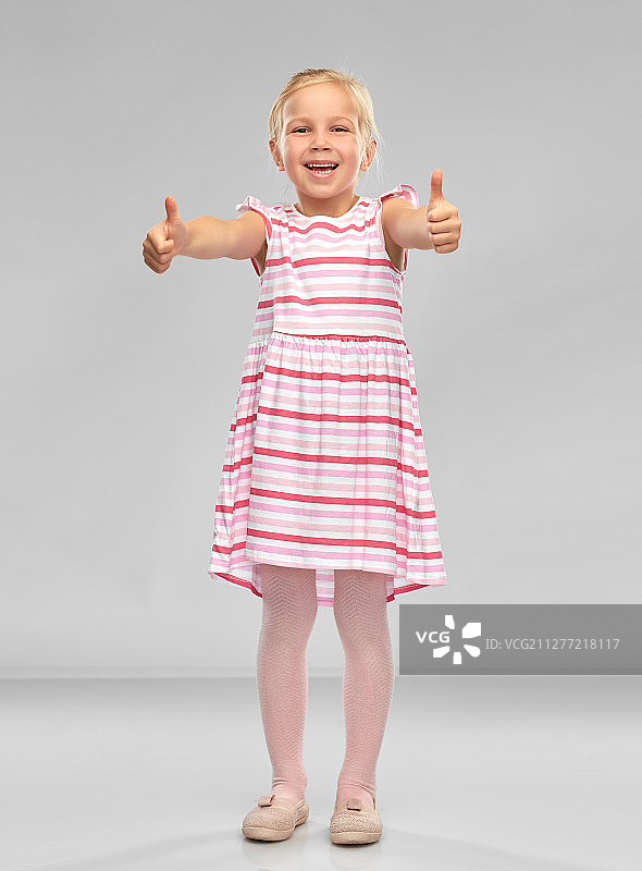 儿童与人物概念：条纹连衣裙的微笑小女孩竖起大拇指图片素材