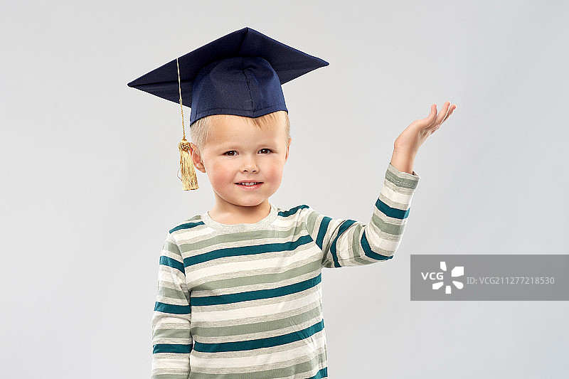 戴着毕业帽，手拿东西的快乐小男孩图片素材