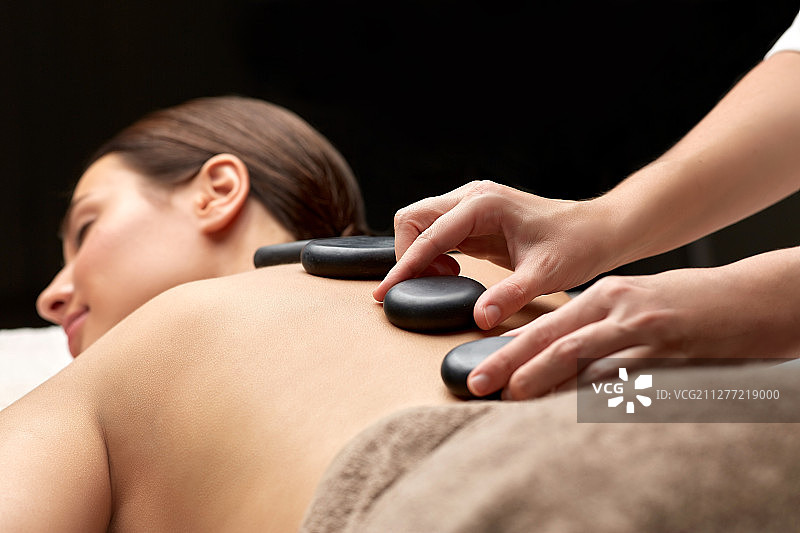 美容和身体护理概念：女子在水疗中心享受热石按摩图片素材