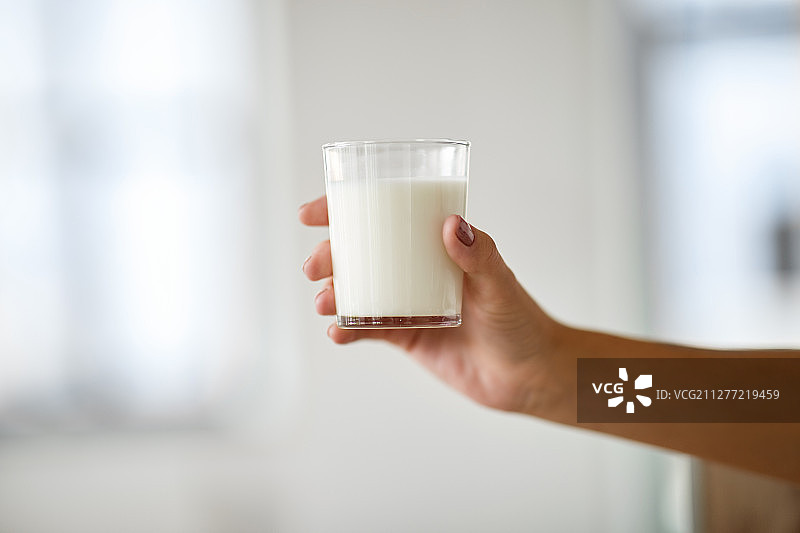 食物、饮食和乳制品概念——女性手持一杯牛奶特写图片素材