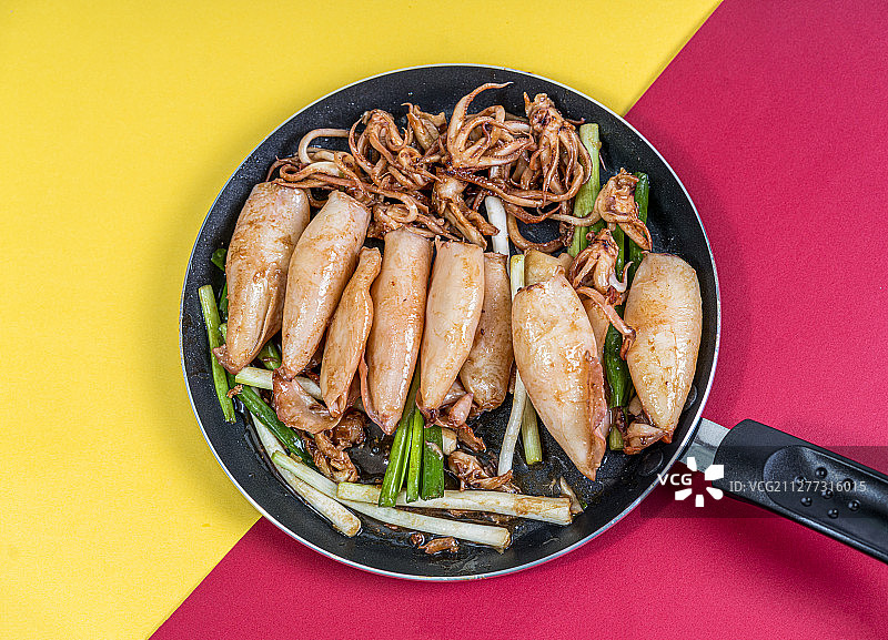 红黄背景里的平底锅中装着爆炒鱿鱼图片素材