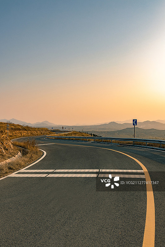 日落时蜿蜒曲折的无人山间公路图片素材