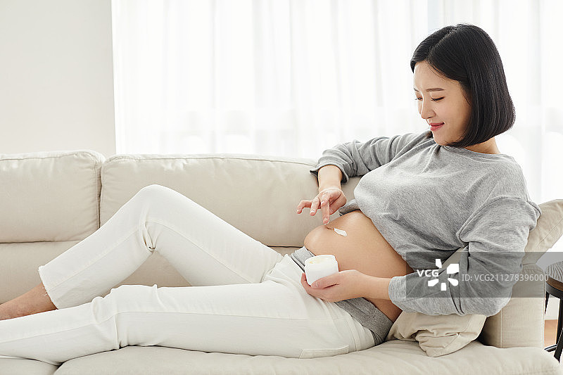 怀孕、微笑、期待：使用润肤露预防妊娠纹图片素材