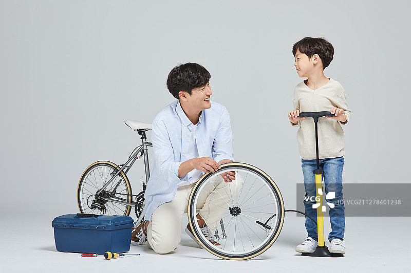 爸爸、儿子和孩子一起修理自行车图片素材