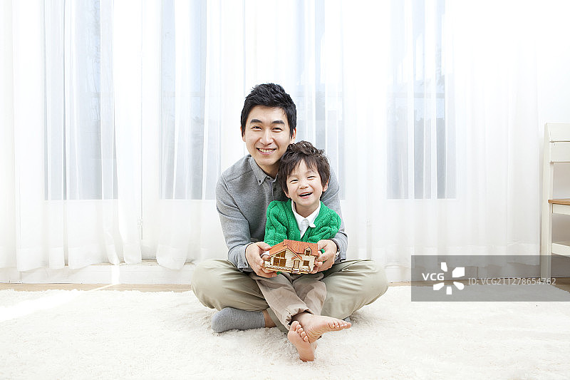 父子坐在地上在客厅里拿着房子模型摄影图片素材
