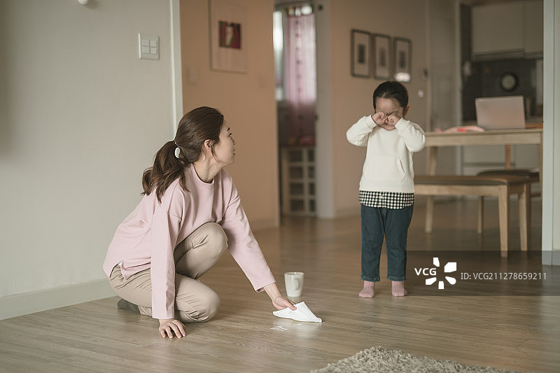 小女孩打翻马克杯里的牛奶，母亲正在擦拭的摄影作品图片素材