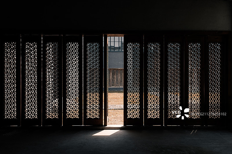 阳光洒进房间，从一扇木雕门的中洒进来图片素材