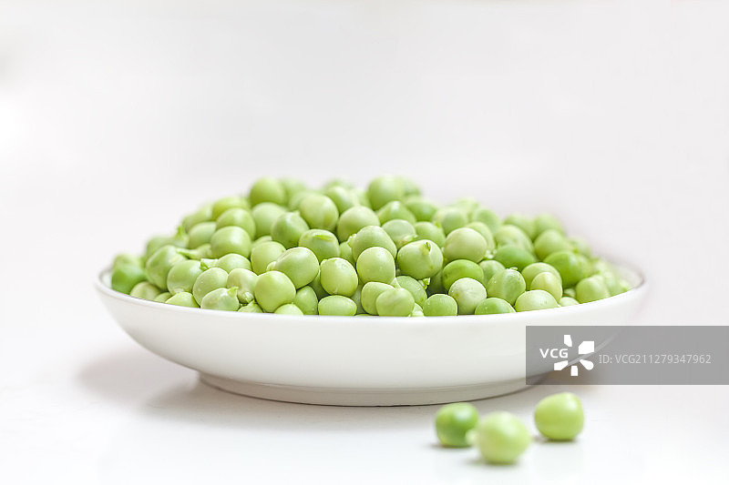 一只白色餐盘里装满了豌豆粒图片素材