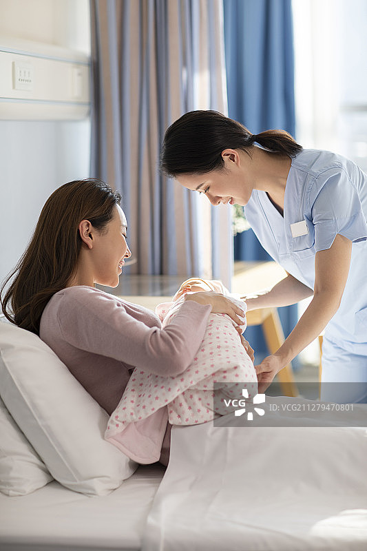 护士把新生婴儿抱给母亲图片素材