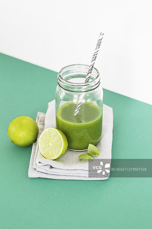 装在玻璃杯中，带有吸管的绿色青柠罗勒冰沙图片素材