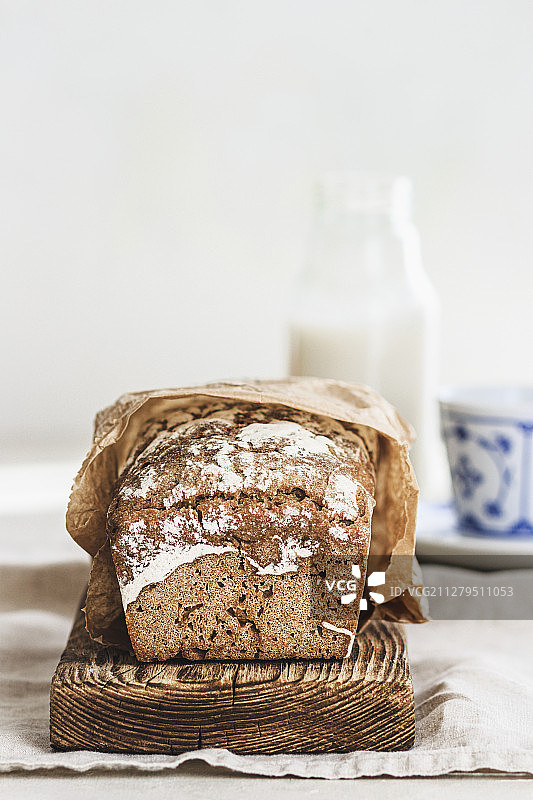 木板上的黑麦面包和背景中的牛奶瓶图片素材