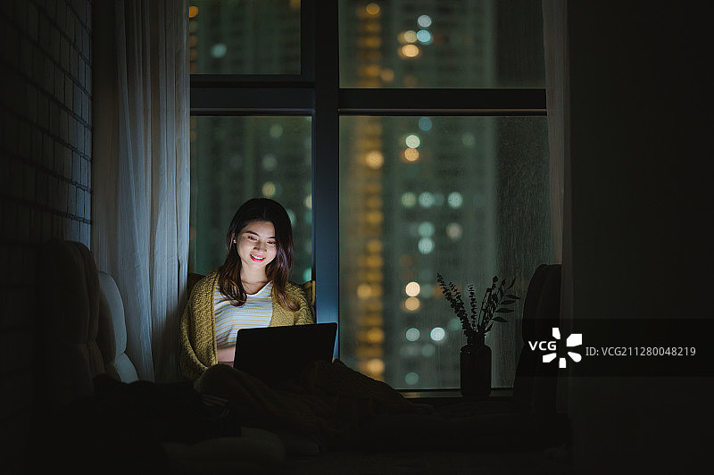亚洲年轻女孩夜晚在家使用笔记本电脑图片素材