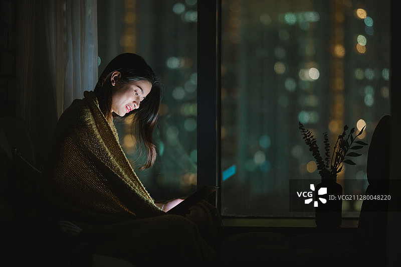 亚洲年轻女孩夜晚在家使用笔记本电脑图片素材