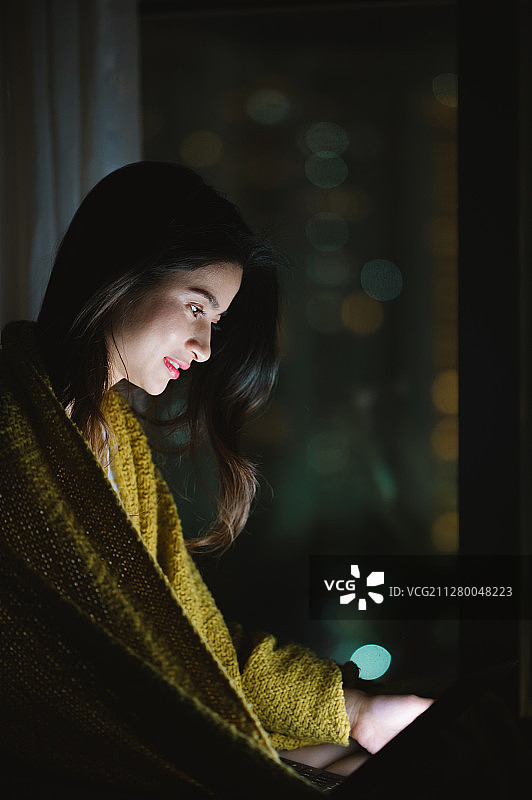 亚洲年轻女孩夜晚在家使用笔记本电脑图片素材