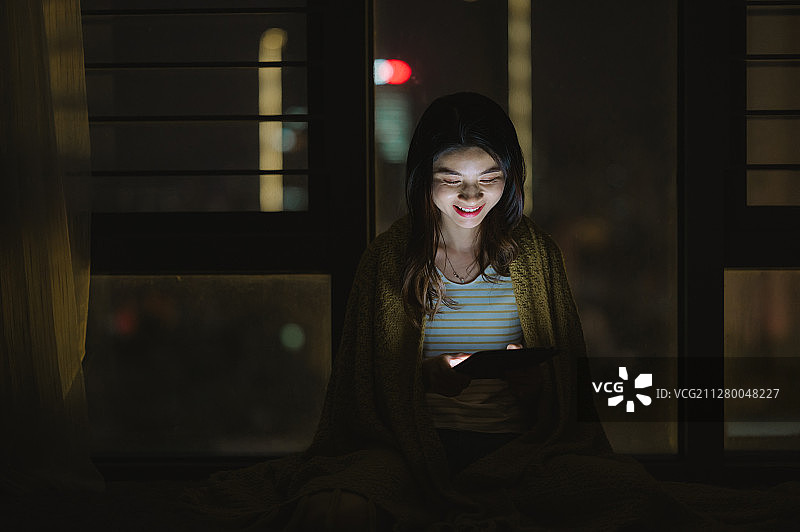 亚洲年轻女孩夜晚在家使用笔记本电脑图片素材