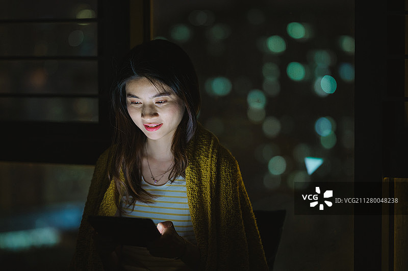 亚洲年轻女孩夜晚在家使用笔记本电脑图片素材