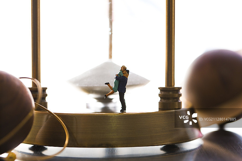 拥抱情侣小玩偶、时间沙漏和运行行星静物图片素材