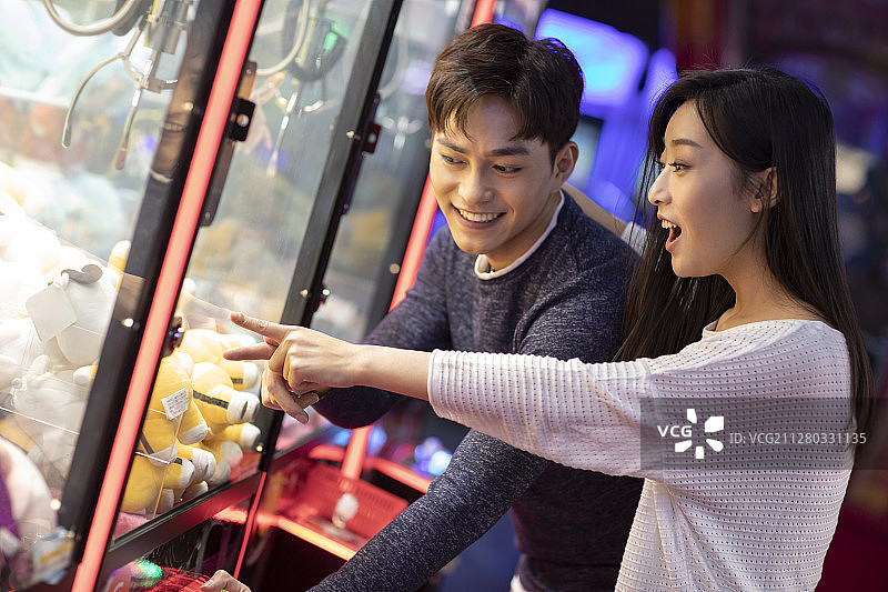 快乐的年轻情侣玩街机游戏图片素材