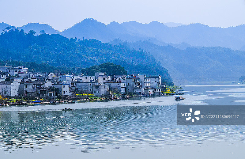 春季的新安江，小船行在江中，江畔山村宁静，远山青翠。图片素材