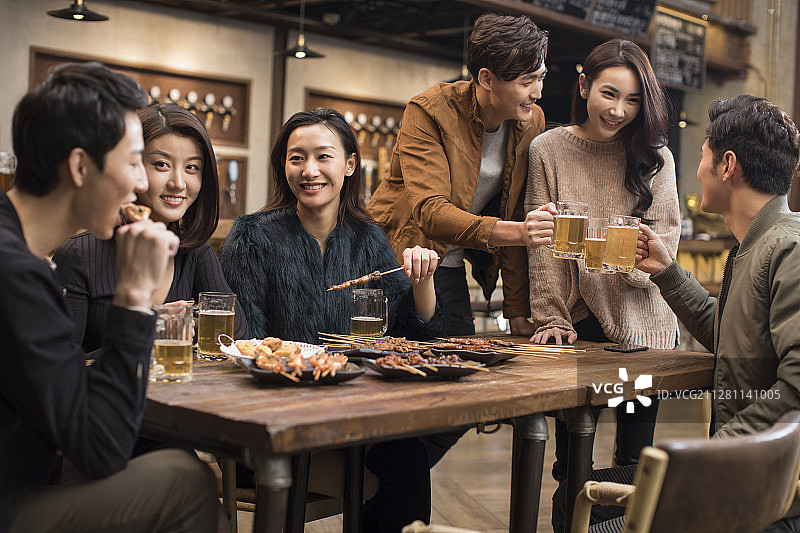 快乐的朋友们在酒吧喝酒吃烧烤图片素材