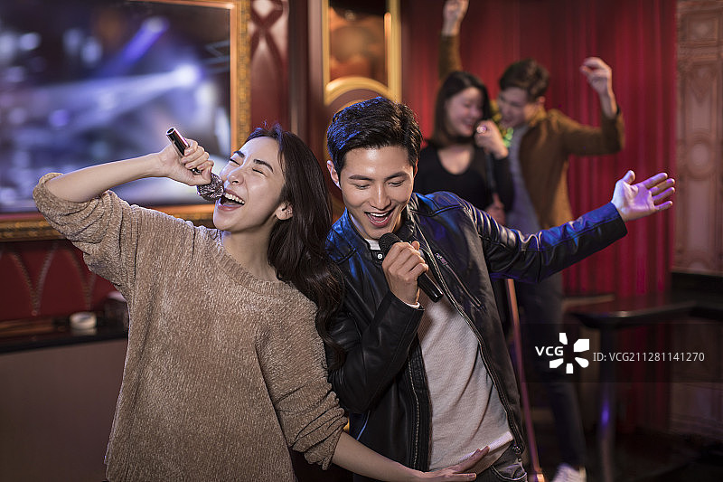 快乐的年轻情侣在KTV唱歌图片素材