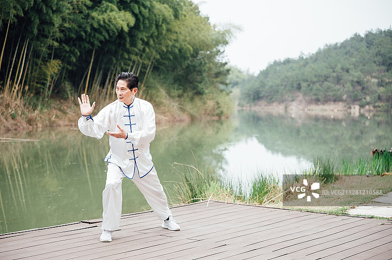 亚洲老年男性在湖边打太极拳图片素材