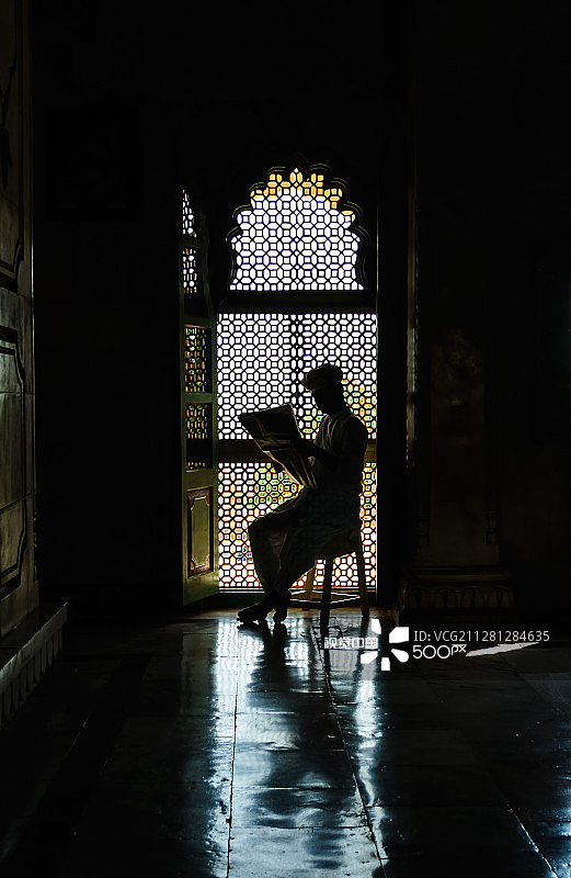 男人在窗前阅读报纸。图片素材