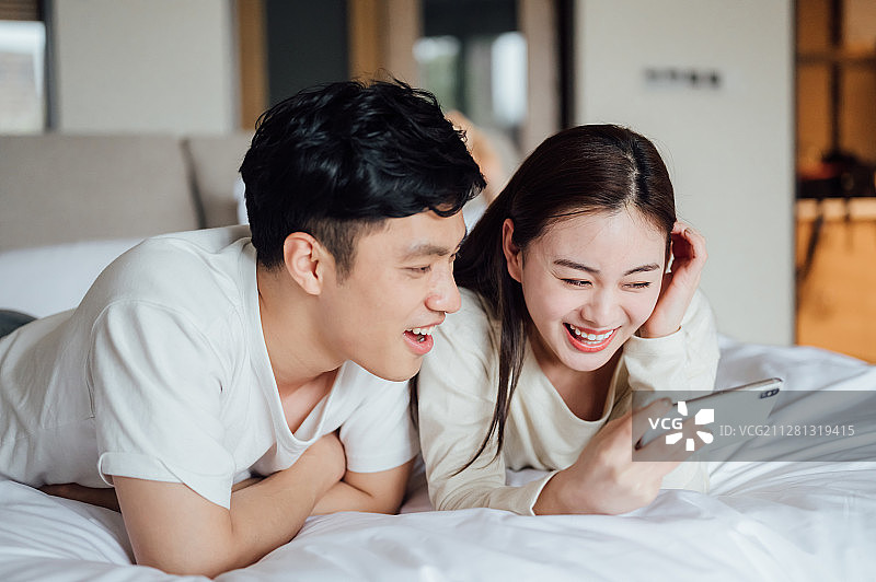 亚洲年轻情侣在家使用智能手机图片素材