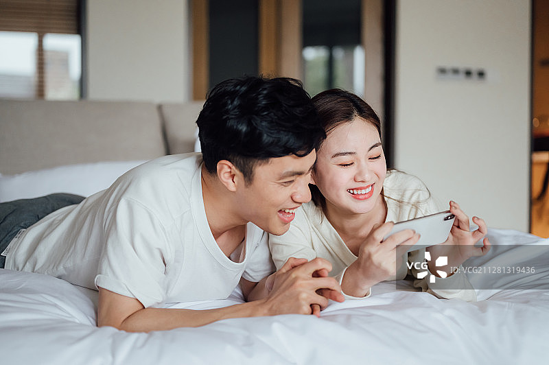 亚洲年轻情侣在家使用智能手机图片素材