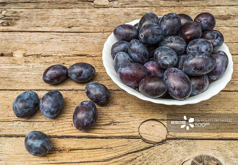 装满新鲜李子的木质背景盘子图片素材