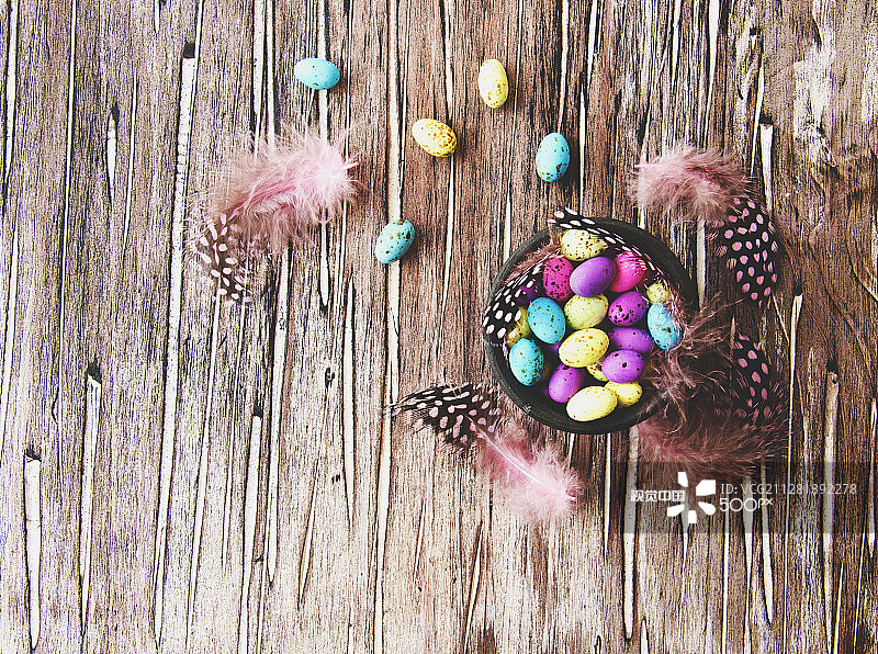 复活节彩色彩蛋、羽毛、蓝色木板图片素材