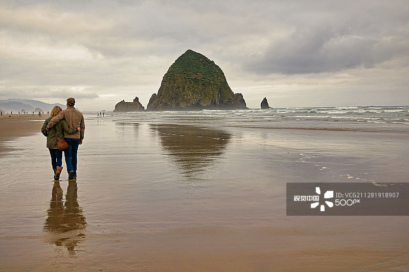 情侣在俄勒冈州坎农海滩散步图片素材