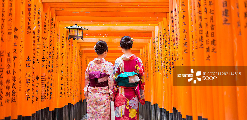 京都伏见稻荷大社红色鸟居下的两位艺伎图片素材