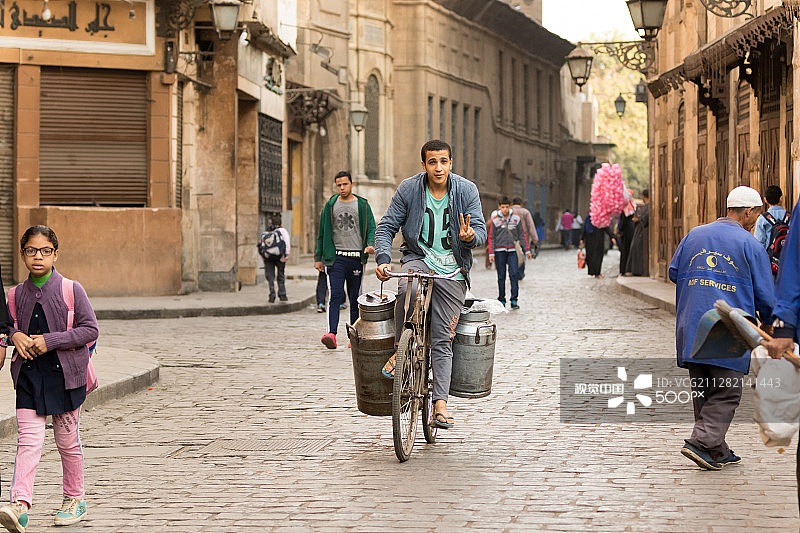 在EL-Moez街清晨骑自行车的送奶工人图片素材