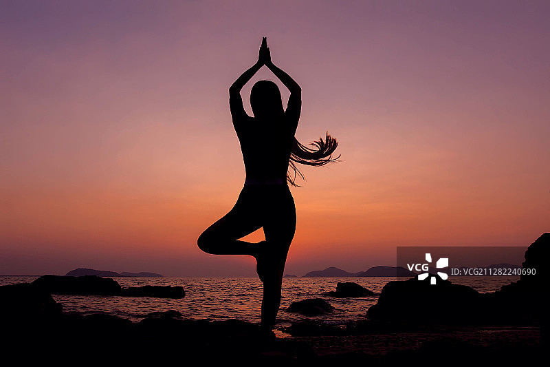 女人在日出时于海边练习瑜伽图片素材