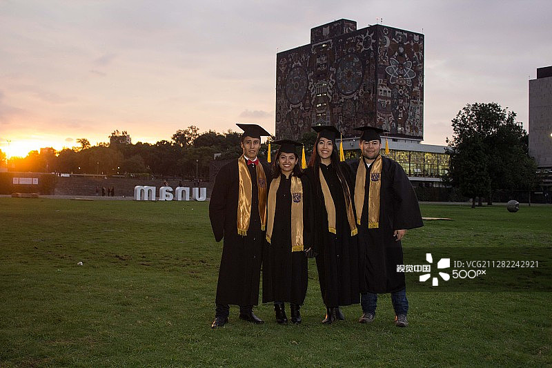 穿着毕业礼服的朋友站在草地上图片素材