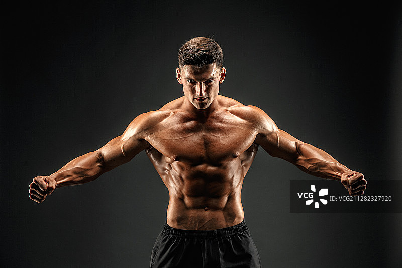 在深色背景下怒吼以激励的健壮男人图片素材