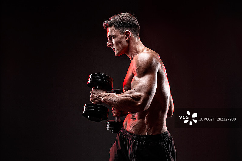 专注用哑铃锻炼的健壮男人图片素材