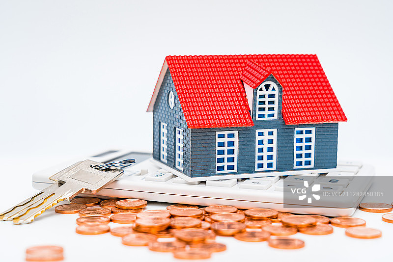 白色背景下的房子模型、计算器、钱币和钥匙——买房概念图片图片素材