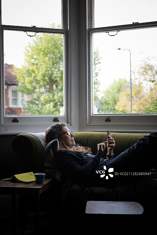 在家用手机的沙发上的中年妇女图片素材