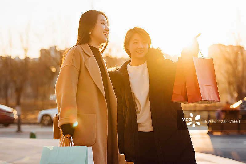 两位正在逛街的年轻亚洲女性在夕阳下图片素材