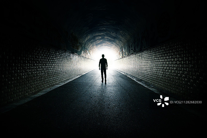 一个男人从黑暗的通道里走向光明图片素材